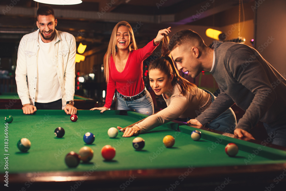 Group of friends play billiards at night out - obrazy, fototapety, plakaty 