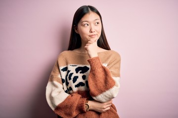 Wall Mural - Young beautiful asian woman wearing animal print fashion sweater over pink isolated background with hand on chin thinking about question, pensive expression. Smiling with thoughtful face. Doubt