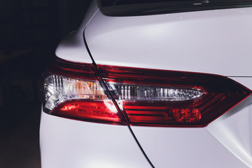 Close up of taillight detail of modern luxury sportscar with reflection on white paint after wash wax. Rear view of supercar break lights. Concept of car detailing and paint protection background.