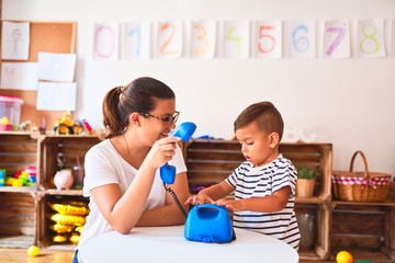 Poster - Beautiful teacher and toddler boy playing with vintage blue phone at kindergarten