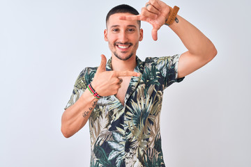 Wall Mural - Young handsome man wearing Hawaiian summer shirt over isolated background smiling making frame with hands and fingers with happy face. Creativity and photography concept.