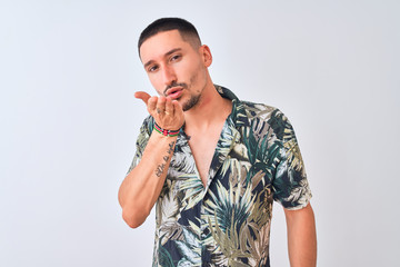 Poster - Young handsome man wearing Hawaiian summer shirt over isolated background looking at the camera blowing a kiss with hand on air being lovely and sexy. Love expression.