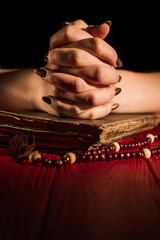 Wall Mural - Dialogue with God concept. Close-up folded young female hands with old book and rosary beads.