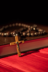 Wall Mural - Close up wooden cross with golden shiny jesus crucifix. Holy bible and rosary on the red table.