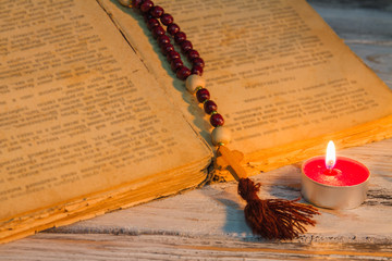 Wall Mural - Open ancient manuscript with rosary and small candle. Worship, reading bible and serving to God.