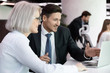 © fizkes - Smiling businessman showing project presentation to mature client.