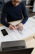 © YURII MASLAK - Architect working in office with blueprints.Engineer inspect architectural plan, sketching a construction project.Portrait of handsome bearded man sitting at workplace. Business construction concept.