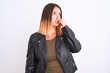 © Krakenimages.com - Young beautiful woman wearing t-shirt and jacket standing over isolated white background looking stressed and nervous with hands on mouth biting nails. Anxiety problem.