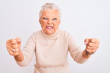 Senior Grey-haired Woman Wearing Turtleneck Sweater Standing Over Isolated White Background Angry And Mad Raising Fists Frustrated And Furious While Shouting With Anger. Rage And Aggressive Concept.