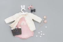 Pink Bodysuit With Knitted Jumper, Kids Handbag Shape Of Crown On Cute Hanger With Bunny Ears. Set Of  Baby Clothes And Accessories  On Gray Background. Fashion Childs Outfit. Flat Lay, Top View