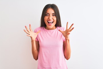 Wall Mural - Young beautiful woman wearing pink casual t-shirt standing over isolated white background celebrating crazy and amazed for success with arms raised and open eyes screaming excited. Winner concept