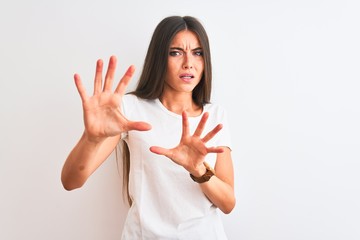 Wall Mural - Young beautiful woman wearing casual t-shirt standing over isolated white background afraid and terrified with fear expression stop gesture with hands, shouting in shock. Panic concept.