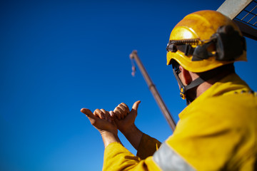 helmet giving crane driver hand signal by holding two hand against each other and pointing both thump out meant crane boom gig out slowly    