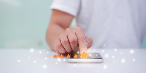 Wall Mural - close up on customer man hand pressing on smartphone screen with gold five star rating feedback icon and press level excellent rank for give score point to review the service business concept	