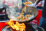 Fototapeta Kuchnia - chef cooks Chinese noodle wok at street food festival