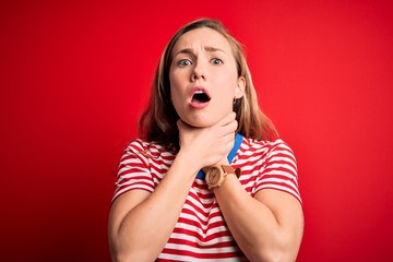 Sticker - Young beautiful blonde woman wearing casual striped t-shirt over isolated red background shouting and suffocate because painful strangle. Health problem. Asphyxiate and suicide concept.