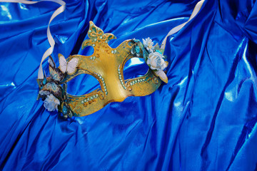 Photo of elegant and delicate Venetian mask over blue silk background