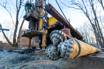 Auger from Hydraulic ground water hole drilling machine installed on the old truck with big wheels on the construction site. Groundwater well drilling.