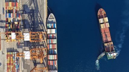 Aerial drone photo of cargo container ship guided by tug assistive boat to Mediterranean logistics commercial port