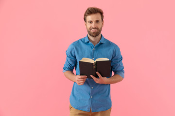 Wall Mural - happy young guy in denim shirt smiling and holding book