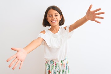 Sticker - Young beautiful child girl wearing casual dress standing over isolated white background looking at the camera smiling with open arms for hug. Cheerful expression embracing happiness.