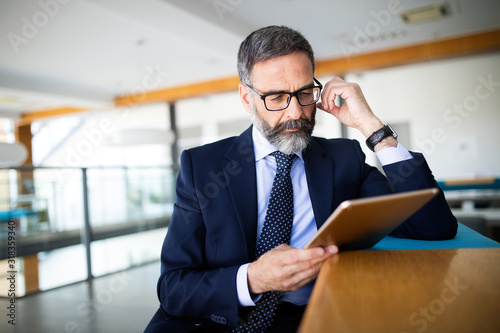 Cuadros en Lienzo Mature handsome business man using a digital tablet at office