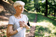 © NDABCREATIVITY - Senior woman with chest pain suffering from heart attack during jogging