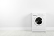 Modern washing machine near white wall, space for text. Laundry day