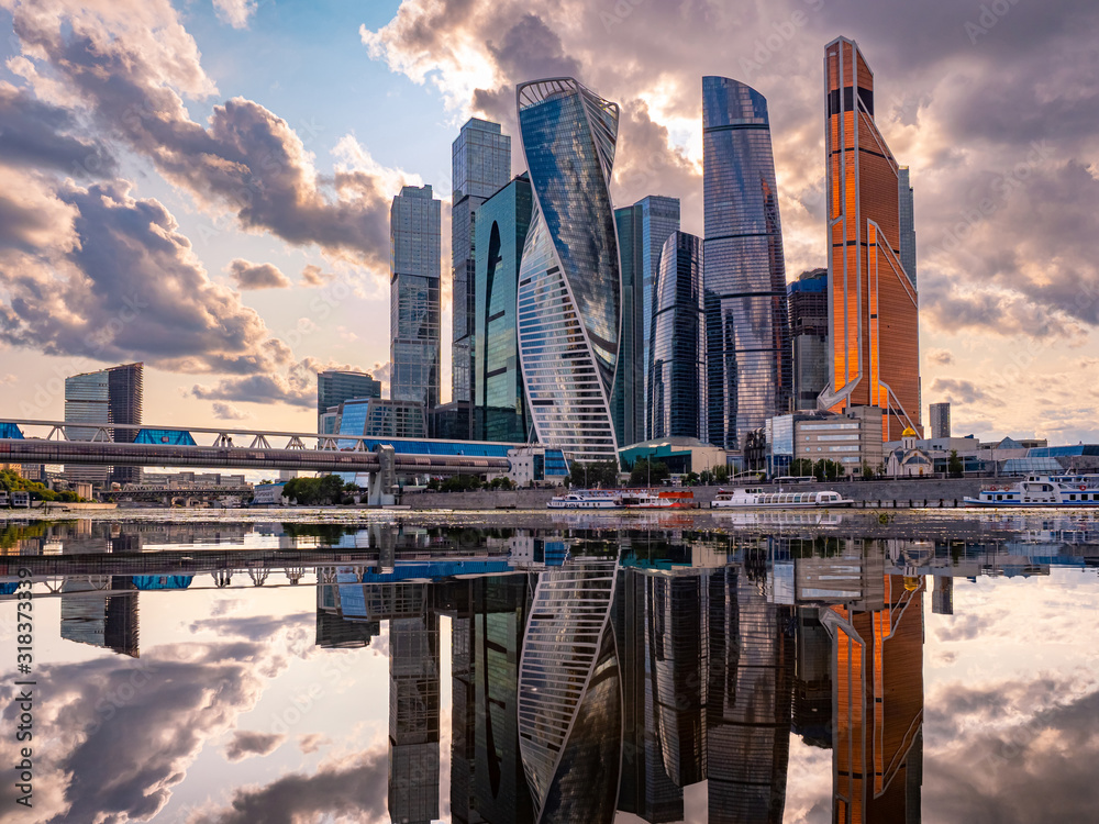 Urban landscape of steel color. Skyscrapers of Moscow are reflected in the water. Moskva-city. Tall buildings and gray clouds. Reflection. Panorama of modern Moscow. - obrazy, fototapety, plakaty 
