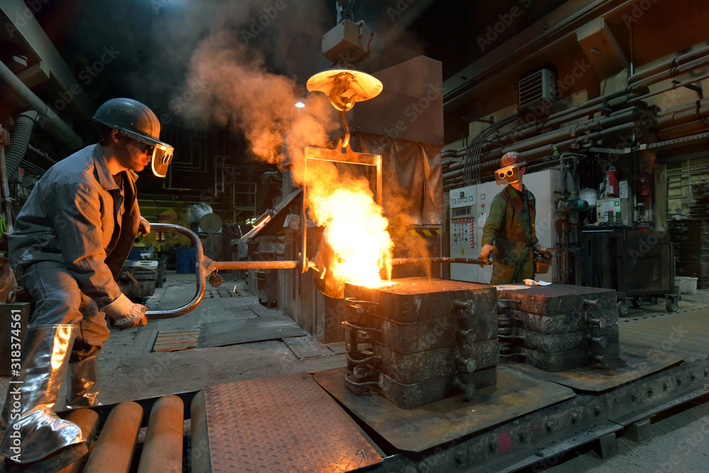 workers in a foundry casting a metal workpiece - safety at work and teamwork - obrazy, fototapety, plakaty 