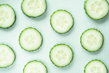 Pattern with freshly cut cucumber slices on green background