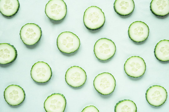 pattern with freshly cut cucumber slices on green background