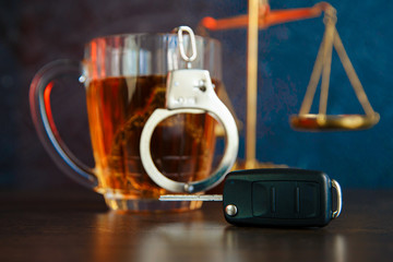 The concept of a DUI. Law hammer, alcohol and car keys on wooden table, dark background