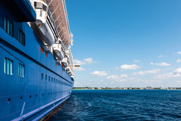 Side of a blue cruise ship that is anchored in the harbor of Grand Cayman, Cayman Islands.