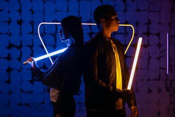 Wall Mural - Young couple with neon lamps on dark color background