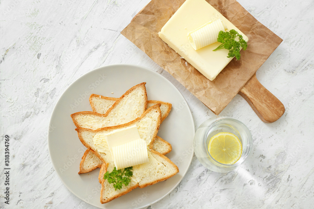 Plate with slices of bread and fresh butter on white background