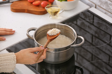 Woman preparing tasty rice in kitchen