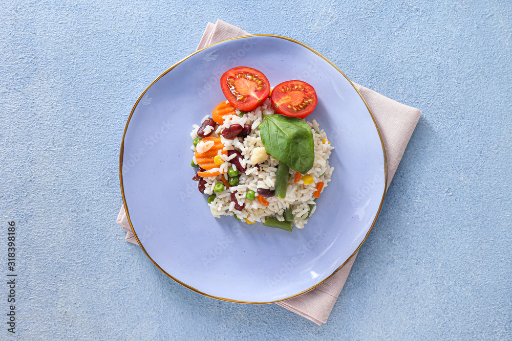 Plate with boiled rice and vegetables on color background