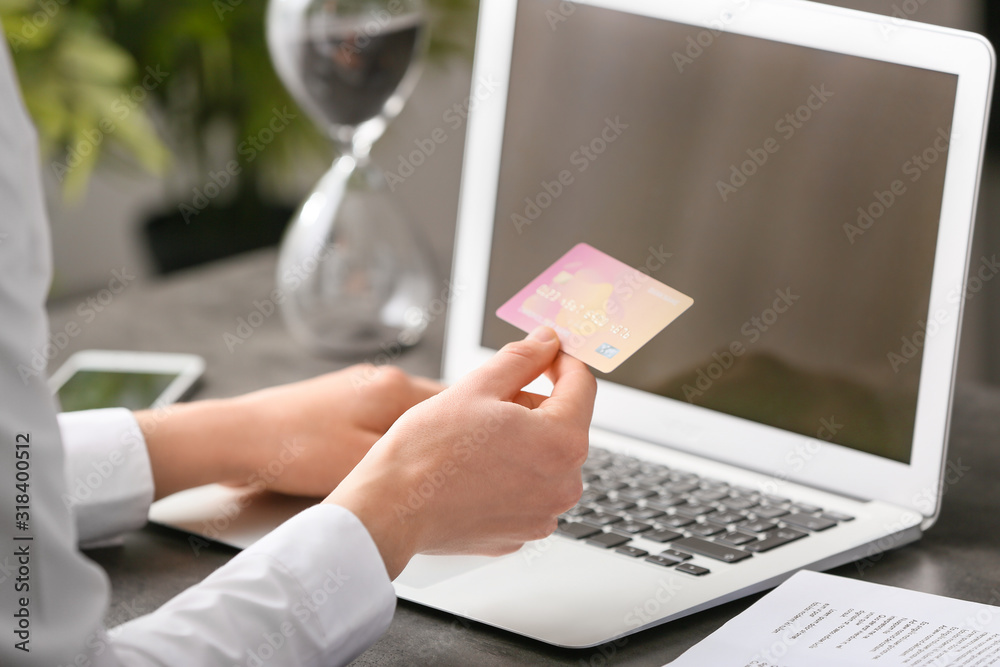 Woman with laptop and credit card at table, closeup