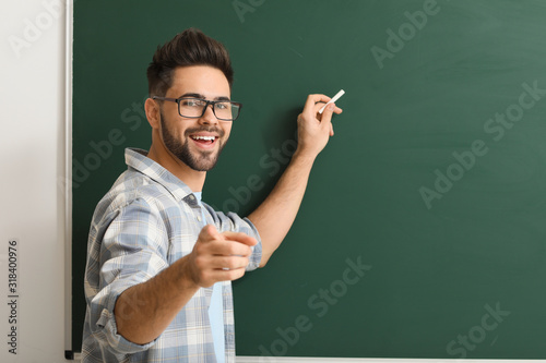 Fotografía Male teacher writing on blackboard in classroom