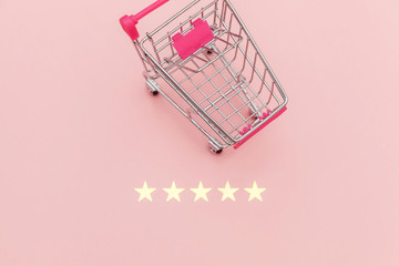 Small supermarket grocery push cart for shopping toy with wheels and 5 stars rating isolated on pastel pink background. Retail consumer buying online assessment and review concept.