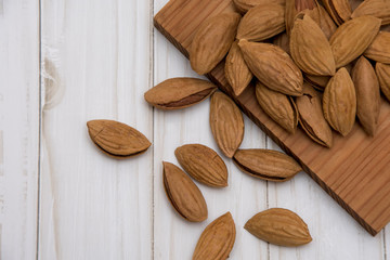 Wall Mural - Dried almonds spilled from a dark plate onto a gray background. healthy food for raw foodists and vegetarians.