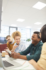 Wall Mural - Multi-ethnic group of students studying in college library, focus on African-American man laughing happily, copy space