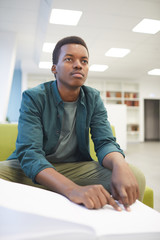 Wall Mural - Portrait of young African-American man reading braille book while studying in school library