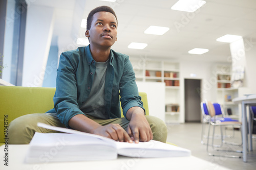 Fotomural Portrait of young African-American man reading braille while studying in school