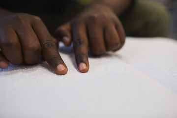 Wall Mural - Closeup of unrecognizable blind African man reading braille book while studying in school, copy space
