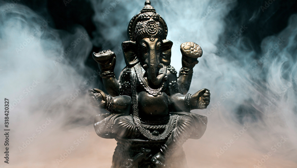 Hindu god Ganesha on black background. Statue with a smoke of incense.  - obrazy, fototapety, plakaty 