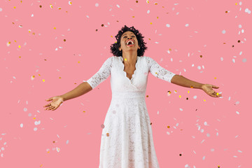 Wall Mural - Portrait of excitement and happiness, happy young woman in white dress and black hair smiling with arms out and confetti falling