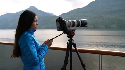 Wall Mural - Travel photographer with professional telephoto lens camera on tripod shooting wildlife in Alaska, USA. Scenic cruising inside passage cruise tourist vacation adventure. Woman taking photo picture.