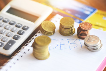 Calculator and coin stack on notebook paper with debt credit card at the office financial counting / debt management concept